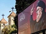 TOPSHOT - A drawing of Hassan Nasrallah, the slain leader of the Lebanese group Hezbollah who was killed days earlier in an Israeli air strike on Beirut's southern suburbs, is depicted next to a condolence message signed by Syria's President Bashar al-Assad on a billboard near a church in Damascus on October 1, 2024. (Photo by LOUAI BESHARA / AFP)