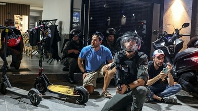 Israeli police and border police take cover during sirens, after Iran fired a salvo of ballistic missiles at Israel, and near the site of a fatal shooting attack in Jaffa, Israel. (Reuters)