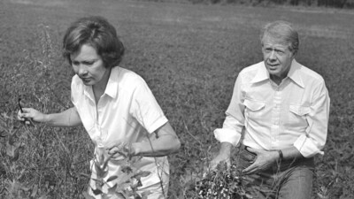 President Jimmy Carter carries a peanut plant as he follows his wife Rosalynn from the field at their Webster County, Ga., farm on August 19, 1978. (AP Photo/Jim Wells, File) (AP)