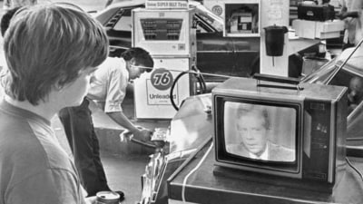 College student Chuck McManis watches President Jimmy Carter's nationally televised energy speech from a service station in Los Angeles, as a gas station attendant fills up a customer's car, July 15, 1979. (AP Photo/Mao, File) (AP)