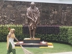 A worker sweeps an area near a statue of Mahatma Gandhi inside the Rashtriya Swachhata Kendra. (PTI)