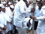 The worker bent down to take off the CM Siddaramaiah's shoes before he entered the memorial.