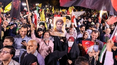 A woman holds a sign showing the face of the Lebanese group Hezbollah's slain leader Hassan Nasrallah with the Persian slogan "Hezbollah is alive", during a rally celebrating after Iran launched a barrage of missiles at Israel in response to the killings of Nasrallah and other Iran-backed militants outside Imam Jaafar Sadiq Mosque in Tehran's Palestine Square on October 1, 2024. (AFP)