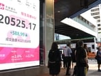 Pedestrians walk past a sign showing the numbers of the Hang Seng Index in Hong Kong.