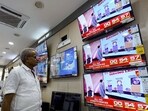 A man watching television waits for the release of exit polls published after voting concluded. 