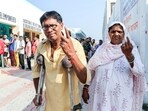 A woman escorts a crutch user as he arrives to cast his vote in Jammu.