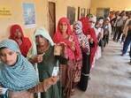People wait in queues at a polling station to cast votes for Haryana Assembly elections, in Faridabad
