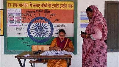 A booth-level officer helps a woman verify her name in the voting list outside a polling station during the state assembly elections, in Karnal. (REUTERS) A booth-level officer helps a woman verify her name in the voting list outside a polling station during the state assembly elections, in Karnal. (REUTERS)