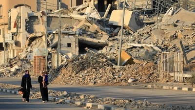 Displaced Palestinians walk past destroyed buildings in al-Bureij refugee camp in the central Gaza Strip. (AFP)
