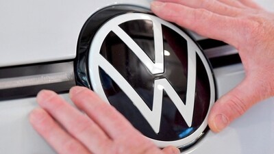 A technician fixes a VW sign in the assembly line of German carmaker Volkswagen's electric ID. 3 car in Dresden, Germany, (Matthias Rietschel/Reuters)