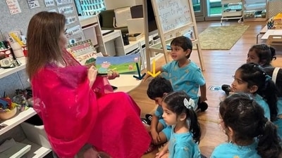 One of the photos showed Nita Ambani sitting on a chair and reading a "Peppa Pig" book to the children who are seen smiling (Instagram/AmbaniUpdate) One of the photos showed Nita Ambani sitting on a chair and reading a "Peppa Pig" book to the children who are seen smiling (Instagram/AmbaniUpdate)