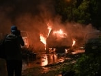 A news cameraman shoots a burning car at the site of an explosion which occured near Karachi airport in Karachi, on late October 6, 2024. 