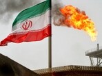 A gas flare is seen alongside an Iranian flag 