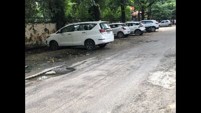 The road with various potholes opposite Vibhuti Khand police station. (HT)