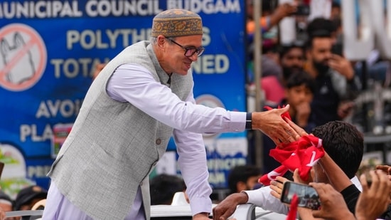 Jammu and Kashmir National Conference (JKNC) party leader Omar Abdullah, standing in car shakes hands with supporters as he celebrates his victory. (AP)
