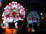 A person takes a snap of Indian artists dressed as Hindu deities Rama, left, and Lakshman, right, sitting on a chariot during a religious procession in the northern Indian state of Uttar Pradesh, India, Wednesday, Oct. 9, 2024. (AP Photo/Rajesh Kumar Singh)