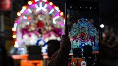 A person takes a snap of Indian artists dressed as Hindu deities Rama, left, and Lakshman, right, sitting on a chariot during a religious procession in the northern Indian state of Uttar Pradesh, India, Wednesday, Oct. 9, 2024. (AP Photo/Rajesh Kumar Singh) (AP)