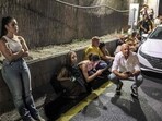 People take cover behind vehicles under a bridge along the side of a highway in Tel Aviv on October 1, 2024.