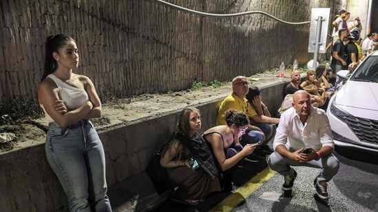 People take cover behind vehicles under a bridge along the side of a highway in Tel Aviv on October 1, 2024. (AFP)