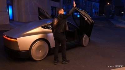 Video grab obtained 10 October, 2024 shows Tesla CEO Elon Musk waving next to his long-promised robotaxi during a launch event at the Warner Brothers studio lot near Los Angeles. (AFP Photo/Tesla) Video grab obtained 10 October, 2024 shows Tesla CEO Elon Musk waving next to his long-promised robotaxi during a launch event at the Warner Brothers studio lot near Los Angeles. (AFP Photo/Tesla)