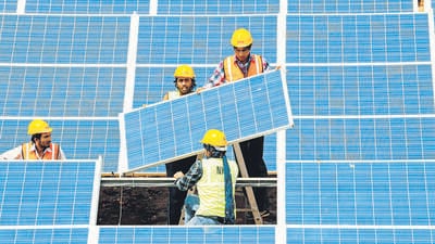 (FILES) - A file picture taken on April 14, 2012 shows Indian workers giving the finishing touches to solar panels at the Gujarat solar park at Charanka village of Patan district, some 250 kms from Ahmedabad. AFP PHOTO / Sam PANTHAKY / FILES (AFP)