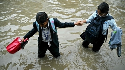 Students wade through a flooded street following heavy rainfall in Bengaluru on October 15, 2024. (AFP) Students wade through a flooded street following heavy rainfall in Bengaluru on October 15, 2024. (AFP)