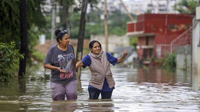 People walk through a flooded street after heavy rainfall in Bengaluru on Wednesday. (PTI) People walk through a flooded street after heavy rainfall in Bengaluru on Wednesday. (PTI)