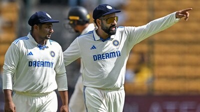 India's captain Rohit Sharma (R) talks to his teammate Sarfaraz Khan during the third day of the first Test cricket match between India and New Zealand (AFP)