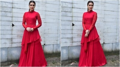 Kriti Sanon's bright red bandhgala kurta is perfect for anyone wanting a minimal yet statement-making look. It features embroidered full sleeves, an embellished belt cinched at the waist, an asymmetric hemline, a pleated dupatta with tassels, and a flared skirt. (HT Photo/Varinder Chawla)