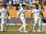 India's Sarfaraz Khan (R) is being greeted by New Zealand's captain Tom Latham (C) after his dismissal during the fourth day of the first Test cricket match between India and New Zealand at the M. Chinnaswamy Stadium in Bengaluru
