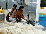 Commuters wade through a flooded road following heavy rainfall in Bengaluru.