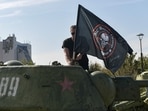 A man mounts a flag of Wagner group on top of an old tank exhibited at the Leninist Komsomol park in Donetsk, Russian-controlled Ukraine, on October 1, 2023, (Photo by STRINGER / AFP)