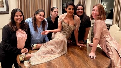 Priyanka Chopra sat on a table and posed as her friends and team members stood next to her. Priyanka Chopra sat on a table and posed as her friends and team members stood next to her.
