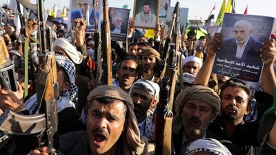 People hold firearms and posters of the late Hamas leader Yahya Sinwar during a rally by protesters, mainly Houthi supporters. (REUTERS)