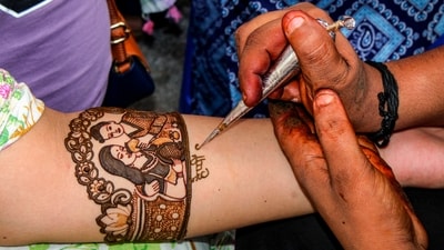 A woman gets her hand decorated with mehendi ahead of the Karwa Chauth festival in Dehradun. Mehendi holds cultural significance in marriage, beginning with the first, much-anticipated mehndi for the wedding. So, it’s no surprise that wearing mehndi for Karwa Chauth, a festival observed for marital bliss, is a celebration in itself, filled with high enthusiasm. (PTI) A woman gets her hand decorated with mehendi ahead of the Karwa Chauth festival in Dehradun. Mehendi holds cultural significance in marriage, beginning with the first, much-anticipated mehndi for the wedding. So, it’s no surprise that wearing mehndi for Karwa Chauth, a festival observed for marital bliss, is a celebration in itself, filled with high enthusiasm. (PTI)