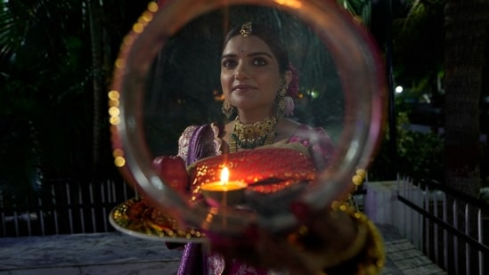 Karwa Chauth moon time live:  A woman looks at the moon through a sieve as part of a ritual to break her fast during Karwa Chauth festival in Jammu.