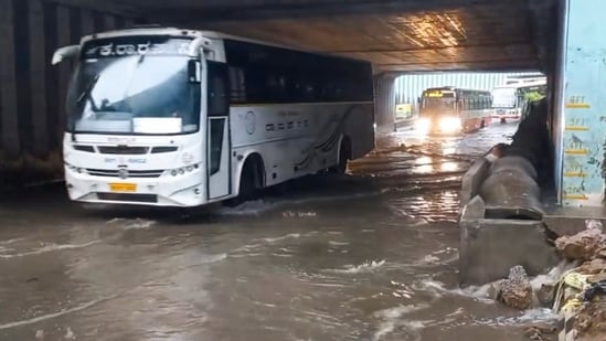 Vehicles move on a waterlogged road after heavy rain, in Bengaluru, Monday, (PTI)