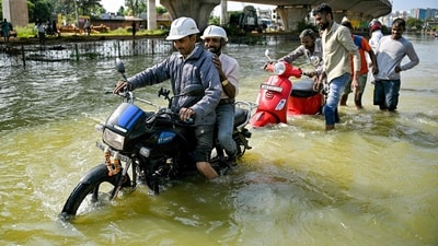 Commuters wade through a flooded street following heavy rainfall, in Bengaluru. (AFP)