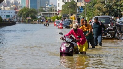 Commuters push their two-wheelers through a waterlogged road after heavy rain, near Kendriya Vihar apartment in Bengaluru on Tuesday. (PTI) Commuters push their two-wheelers through a waterlogged road after heavy rain, near Kendriya Vihar apartment in Bengaluru on Tuesday. (PTI)