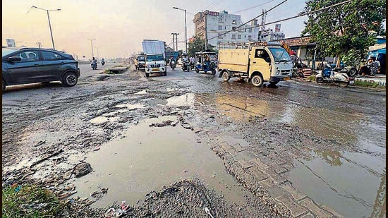 Commuters navigate through pothole-riddled service lane on Ludhiana-Jalandhar highway. (HT Photo)