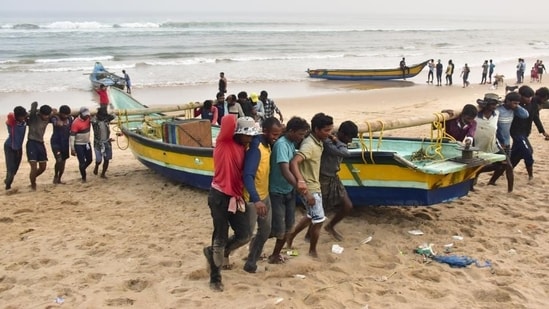 Fishermen shift their boats in anticipation of Cyclone Dana in Odisha’s Puri on Monday. (PTI)