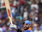 Virat Kohli raises his bat after reaching the landmark of 10,000 runs in one-day internationals during the second ODI match against West Indies in Visakhapatnam.