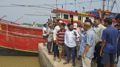 Fishermen attempt to bring their boat back to shore during high tide before Cyclone Dana makes landfall in Bhadrak district. (PTI) Fishermen attempt to bring their boat back to shore during high tide before Cyclone Dana makes landfall in Bhadrak district. (PTI)