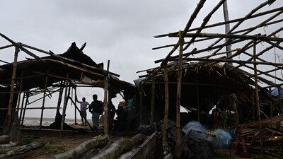 Villagers stand near damaged temporary houses following the landfall of cyclone Dana in East Midnapore district around 180km southwest of Kolkata, on October 25, 2024. Cyclone Dana uprooted trees and power lines after making landfall on India's east coast, with officials warning of more fierce weather on October 25. (Photo by DIBYANGSHU SARKAR / AFP) (AFP) Villagers stand near damaged temporary houses following the landfall of cyclone Dana in East Midnapore district around 180km southwest of Kolkata, on October 25, 2024. Cyclone Dana uprooted trees and power lines after making landfall on India's east coast, with officials warning of more fierce weather on October 25. (Photo by DIBYANGSHU SARKAR / AFP) (AFP)