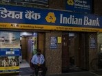 A security guard wearing a protective mask sits at the entrance of an Indian Bank branch at Connaught Place.