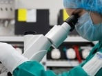 A scientist examines COVID-19 infected cells under a microscope. A scientist examines COVID-19 infected cells under a microscope.