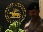 A police officer walks past the Reserve Bank of India (RBI) logo inside its headquarters in Mumbai, India.