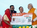 Prime Minister Narendra Modi with Union minister of health and family welfare JP Nadda hands over an 'Ayushman Vaya Vandana Card' to a beneficiary during an event, at All India Institute of Ayurveda (AIIA) in New Delhi on Tuesday. (ANI)