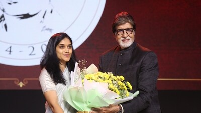 Amitabh Bachchan being fecilitated on stage with a bouquet of flowers at the ceremony. 