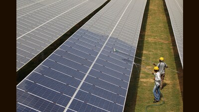 Workers clean photovoltaic panels inside a solar power plant in Gujarat. (REUTERS) Workers clean photovoltaic panels inside a solar power plant in Gujarat. (REUTERS)